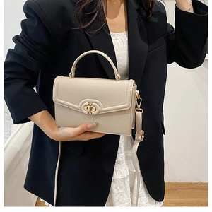 Close-up of beige lychee texture handbag featuring a golden turn-lock and top handle