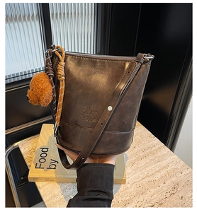 Close-up of vintage dark brown leather bucket bag with embossed logo and teddy bear charm