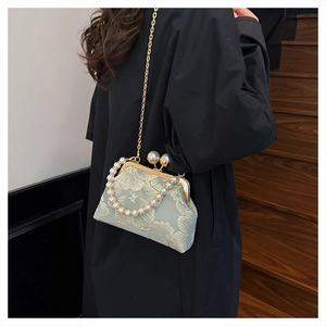 Close-up of light green floral jacquard handbag with pearl handle and gold hardware