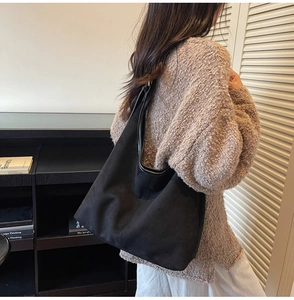 Vue latérale du grand sac hobo noir en daim porté à l'épaule pour le bureau