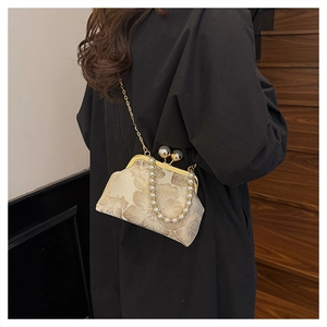 Detail of vintage jacquard handbag with pearl clasp and gold chain shown on a model