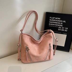 Close-up of pink matte suede bag featuring star-shaped zippers and stylish pocket details