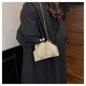 Detail of elegant shell handbag with floral embroidery and pearl handle worn by model
