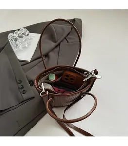 Internal view of brown textured bucket bag showing daily essentials and zip pocket