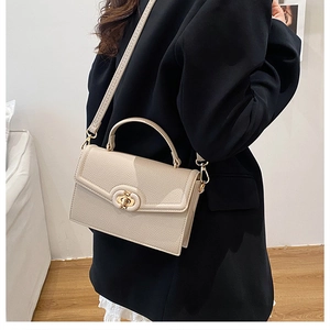 Detail of a beige lychee pattern leather handbag with a vintage gold metal lock