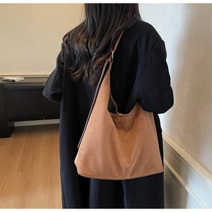 Vue détaillée du grand sac cabas en daim marron porté par un mannequin dans un salon