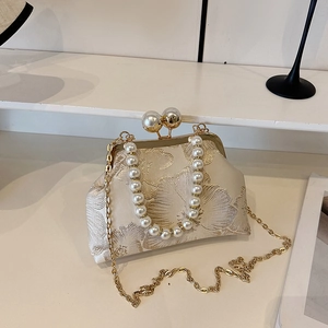 Close-up of floral jacquard fabric with elegant large pearls and golden metal clasp