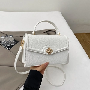 Close-up of white pebble leather handbag with gold metal clasp and circular handle