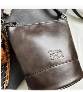 Detail of dark brown vintage leather bucket bag featuring soft texture and plush charm