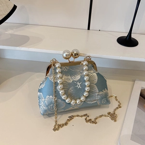 Close-up of light blue floral jacquard fabric with pearl handle and kiss-lock closure