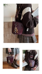 Detail of burgundy woven bucket bag with metal ring handle and beaded tassel pendant