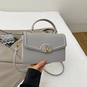 Close-up of gray lychee pattern leather handbag with gold twist lock and handle