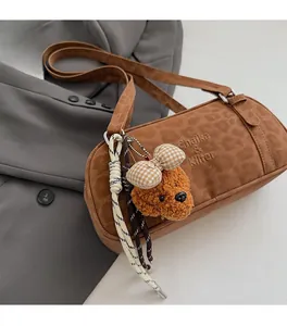 Detail of brown suede bowling bag with teddy bear pendant and woven rope decoration