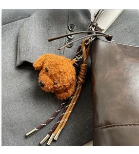Brown curly plush poodle bag charm with woven leather strap on a dark brown handbag