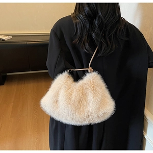 Détail du sac à main en fausse fourrure crème douce avec poignée en cuir sur manteau noir