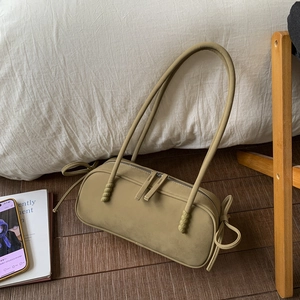 Detail view of olive green cylinder shoulder bag with side bow ties and metal zipper