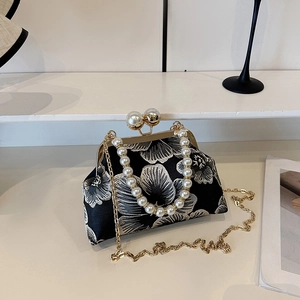 Detailed embroidery of large white floral patterns on a black vintage clutch bag