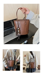 Detail of brown woven bucket bag featuring wooden bead tassel and logo embossing