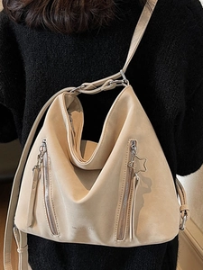 Minimalist beige suede crossbody bag featuring vertical zippers and a star charm