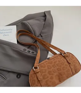 Detail showing brown leopard print cylinder bag with double straps and brand logo
