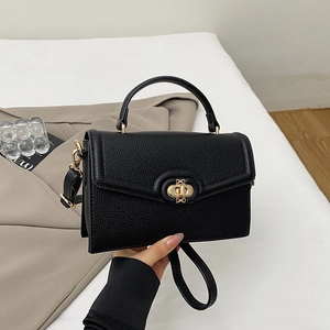 Close-up of black leather handbag with lychee texture and gold metal twist lock buckle