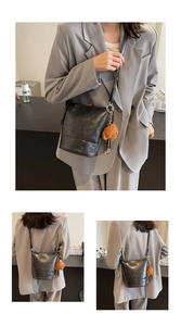 Detail of black leather bucket bag with brown teddy bear charm and adjustable strap