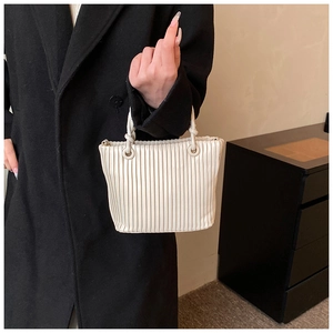 Detail of off-white pleated bucket bag featuring unique twisted rope handle and metal rings