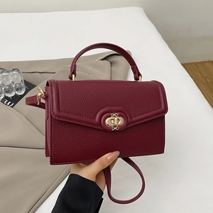 Detail of burgundy litchi grain leather bag with gold hardware and elegant swivel lock