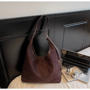 Vue macro du sac cabas en daim marron foncé avec bandoulière réglable et boucle en métal