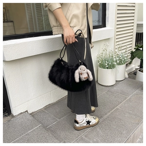 Détail du sac croissant en fausse fourrure noire avec un pendentif lapin en peluche