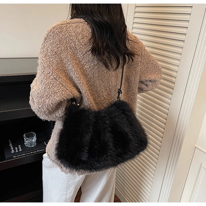 Détail du sac à bandoulière en fausse fourrure noire avec lanière en cuir sur modèle
