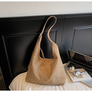 Détail du grand sac cabas en daim kaki sur un lit avec un ordinateur et un casque