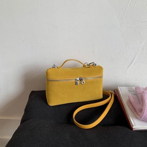 Detailaufnahme einer leuchtend gelben Box-Tasche auf einer weichen grauen Oberfläche