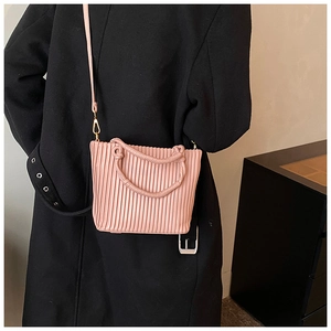 Pink pleated bucket bag worn with black coat showing texture and detachable strap