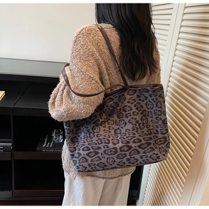 Detail of leopard print tote bag with brown leather strap and logo on model's shoulder