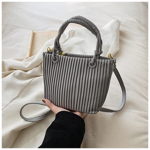 Close-up of dark grey bucket bag with vertical pleats, gold hardware, and shoulder strap