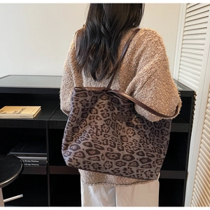 Rear view of a model wearing a large leopard print tote bag with brown knit sweater