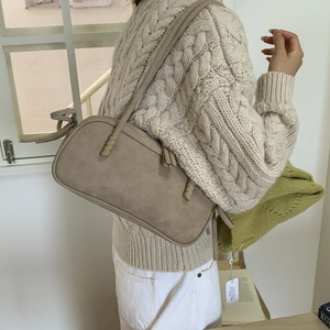 Detail of light brown faux suede underarm bag with a unique spiral twist strap design