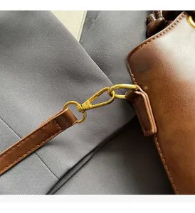 Nahaufnahme der goldenen Metallbeschläge und braunen Ledernähte an einer Handtasche