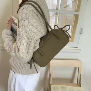 Close-up of olive green matte leather shoulder bag with decorative ribbon bow knot detail