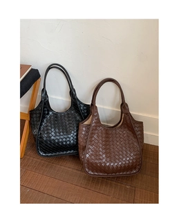 Dettaglio delle borse hobo in pelle intrecciata in nero e marrone scuro su una sedia di legno