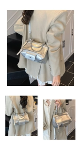 Detail view of silver metallic leather handbag featuring motorcycle style zips and top handles