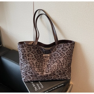 Detail view of leopard print tote bag with metal logo on textured fabric background