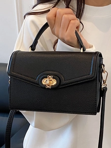 Minimalist black pebble leather satchel bag with golden twist lock and shoulder strap