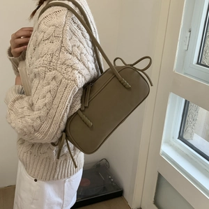 Detail of khaki cylindrical shoulder bag with twisted strap and soft matte leather finish