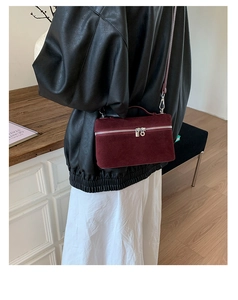 Detail der weinroten Samt-Box-Tasche mit silbernem Doppelreißverschluss und Lederriemen