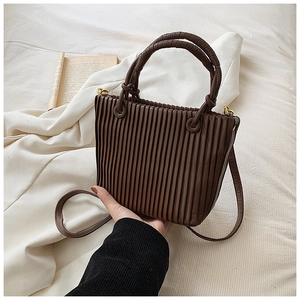 Detailed view of dark brown pleated bucket bag with rich leather texture and gold hardware