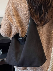Grand sac hobo en daim noir porté par un mannequin, vue de dos au style minimaliste épuré