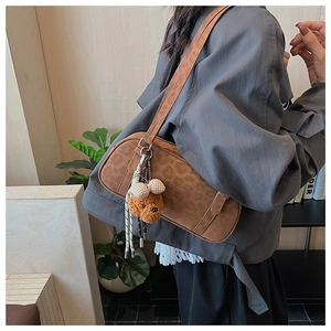 Detail of vintage brown leopard suede shoulder bag with plush bear charm and brand logo
