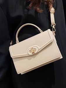 Minimalist beige pebble leather crossbody bag with gold rotary lock and top handle